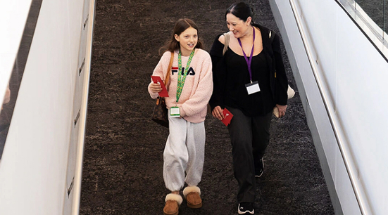 A person with a sunflower lanyard heading down escalators at Adelaide Airport