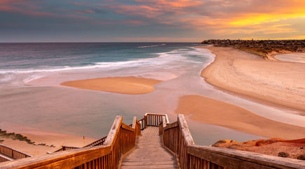 Wooden steps leading down to the beach during sunset