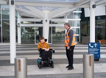 A member of Adelaide Airport staff assisting a person in a power wheelchair.
