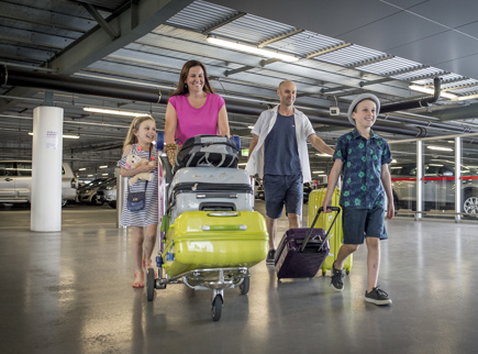 A family walking through the Adelaide Airport car pack with their luggage