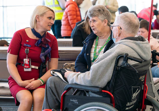 An Adelaide Airport Assistant Staff member talking to a couple, one of which is in a wheelechair.