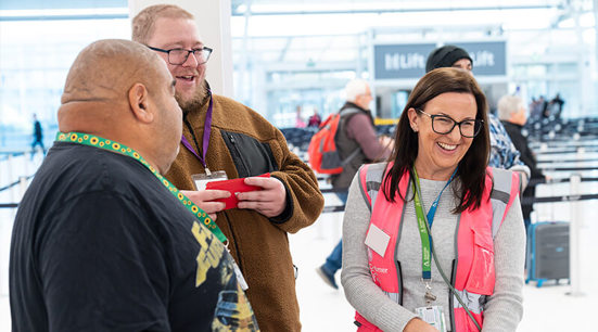 An Adelaide airport employee chatting to a passenger who is wearing a hidden disabilities lanyard