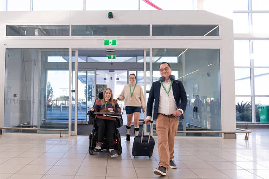 3 people walking into the airport with their hidden disability lanyard