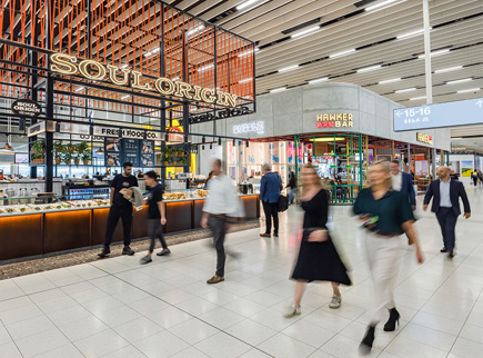 A photo of people walking around the Adelaide Airport terminal with a couple of retailers in the background.