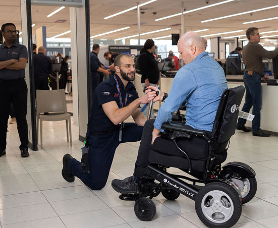 An Adelaide Airport Security staff member helping a person during security screening