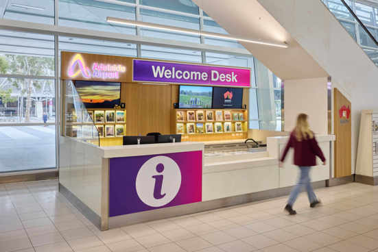 An Adelaide Airport staff member greeting a passenger at the help desk