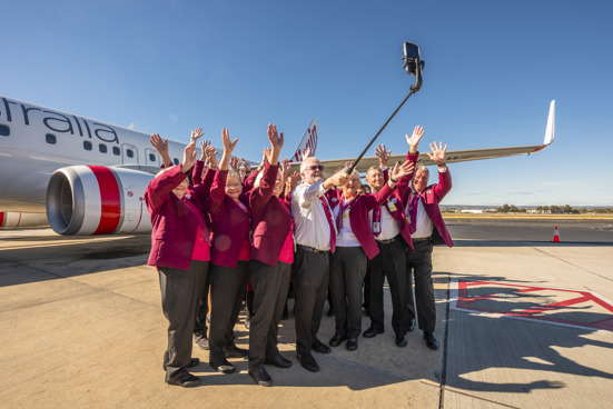 A group of ambassadors getting a photo in front of an aircraft with Richard Branson