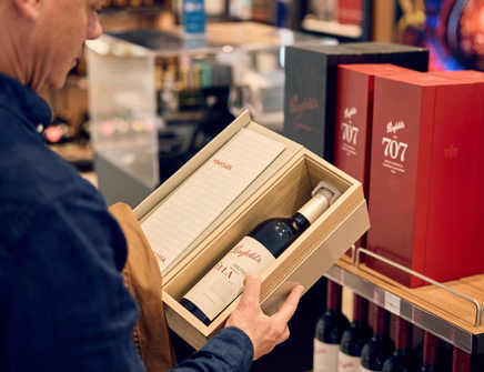 man looks at bottle of wine displayed in a box
