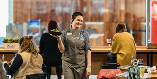 A waitress at the Coopers Alehouse holding a meal that she is taking to a table.